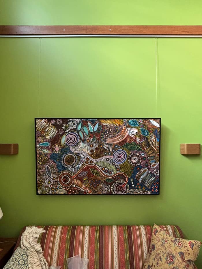 Framed artwork on a green feature wall from a timber-mounted rail