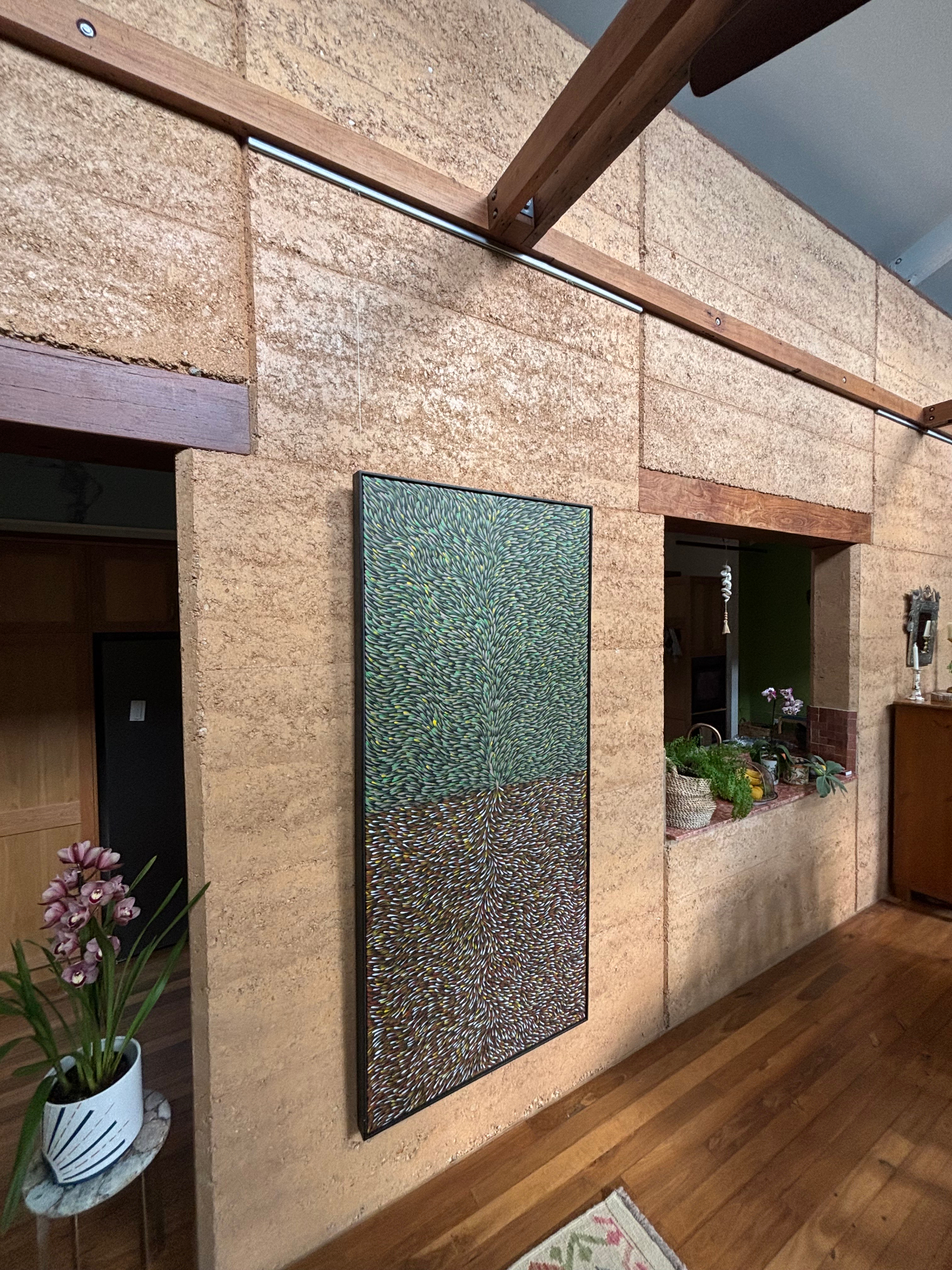 Painting on rammed-earth wall from ceiling rail